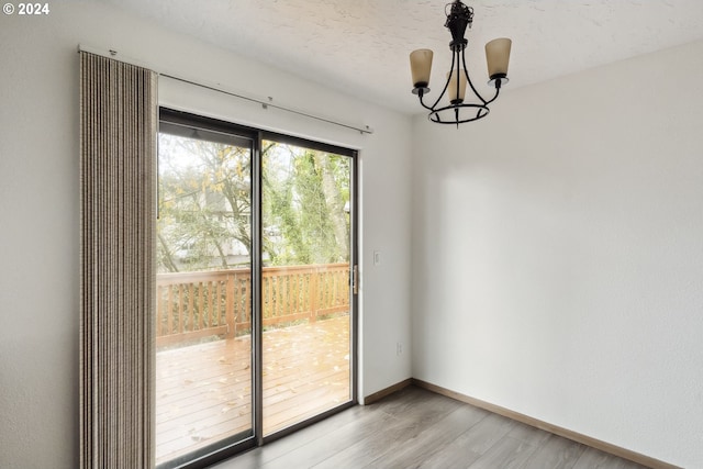 unfurnished dining area featuring a chandelier, a textured ceiling, and light hardwood / wood-style floors