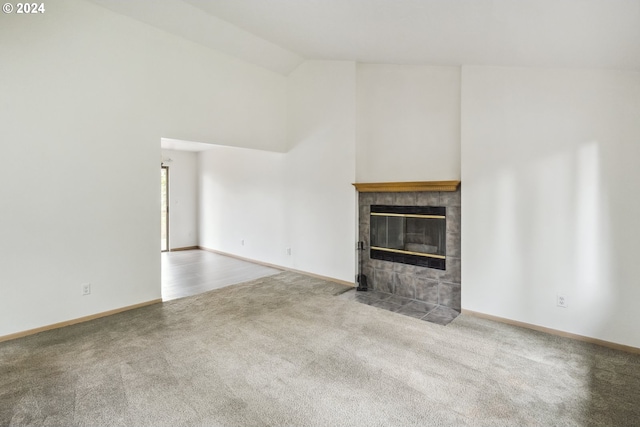 unfurnished living room featuring carpet floors, high vaulted ceiling, and a tiled fireplace