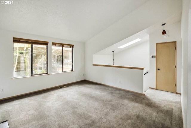 unfurnished living room featuring vaulted ceiling with skylight and light carpet