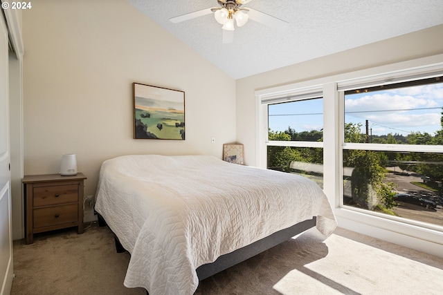 carpeted bedroom with a textured ceiling, ceiling fan, and lofted ceiling