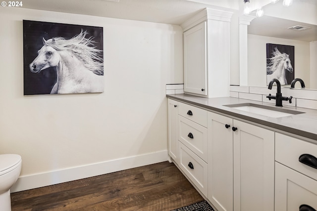 bathroom featuring vanity, hardwood / wood-style flooring, toilet, and backsplash