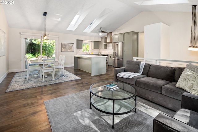 living room featuring ceiling fan, dark wood-type flooring, and lofted ceiling with skylight