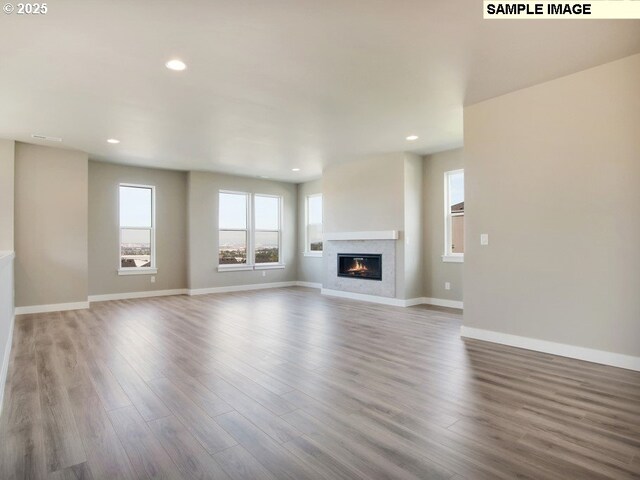 kitchen with light wood-type flooring, built in microwave, wall chimney range hood, white cabinets, and oven