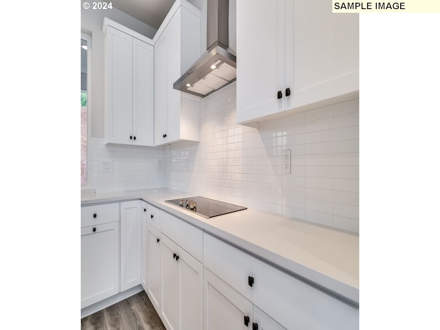 kitchen with decorative backsplash, black electric stovetop, dark wood-type flooring, wall chimney range hood, and white cabinetry