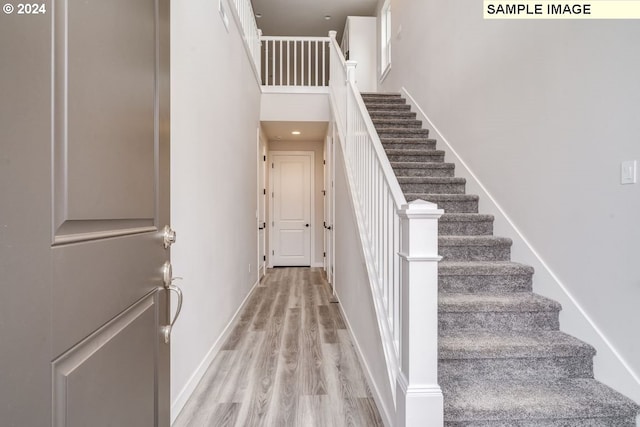 staircase featuring a high ceiling and hardwood / wood-style flooring