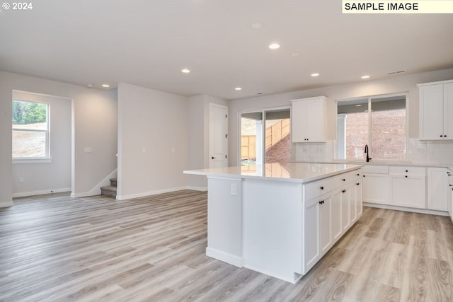 kitchen featuring backsplash, light wood-type flooring, and white cabinets