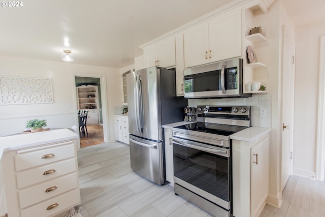 kitchen with white cabinets, appliances with stainless steel finishes, light countertops, open shelves, and backsplash