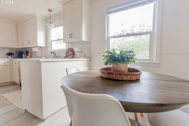 kitchen featuring a peninsula, a breakfast bar, white cabinetry, hanging light fixtures, and light countertops