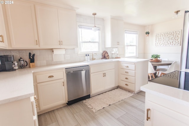 kitchen featuring light countertops, hanging light fixtures, backsplash, a sink, and dishwasher