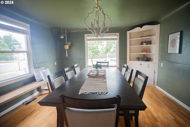 dining area featuring a notable chandelier, plenty of natural light, visible vents, and light wood-style floors