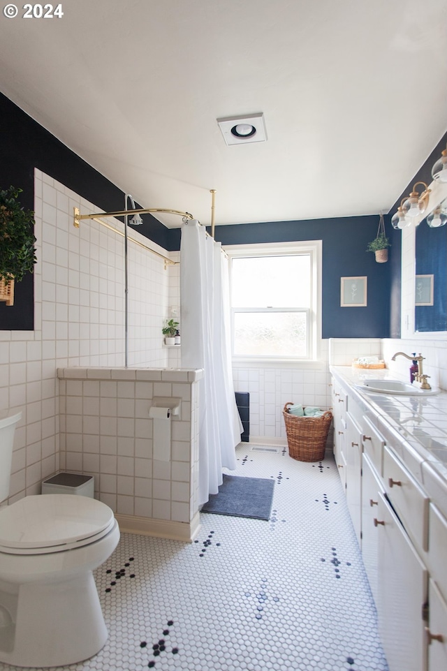 bathroom with toilet, tile patterned flooring, tile walls, and vanity