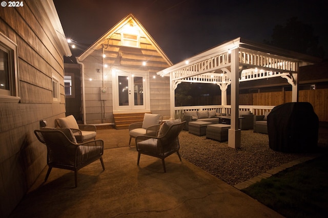 patio at night featuring fence and an outdoor living space