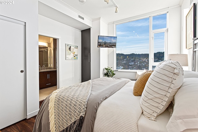 bedroom featuring track lighting, sink, ornamental molding, connected bathroom, and dark hardwood / wood-style flooring