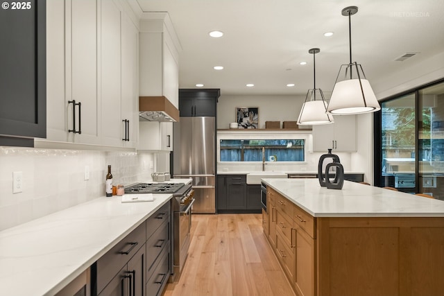 kitchen featuring white cabinets, decorative light fixtures, light stone counters, and stainless steel appliances