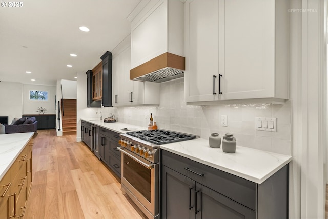 kitchen featuring white cabinets, light stone counters, and high end stainless steel range