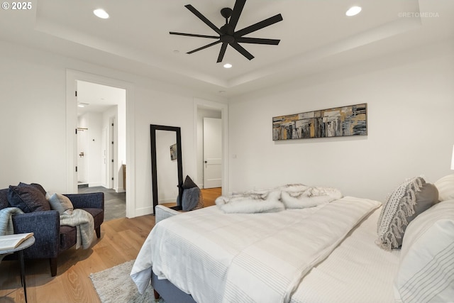 bedroom featuring wood-type flooring, a raised ceiling, and ceiling fan