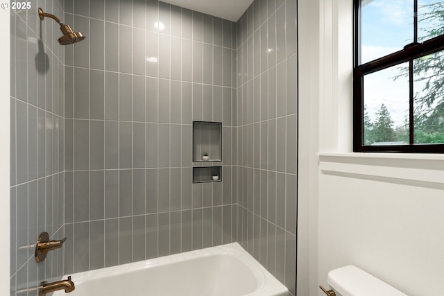 bathroom featuring toilet and tiled shower / bath