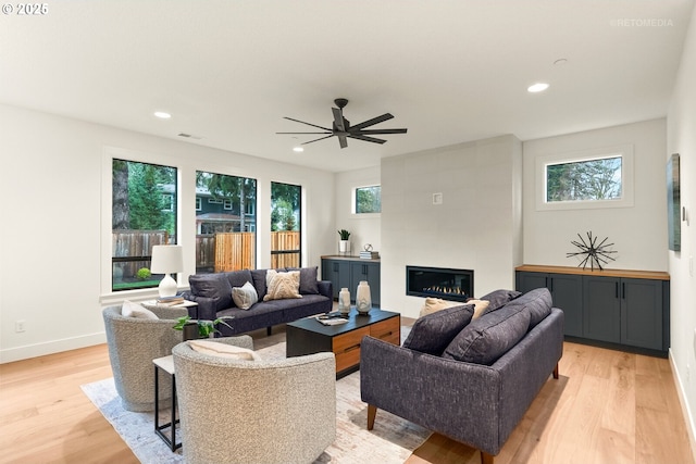 living room with light hardwood / wood-style floors, a healthy amount of sunlight, and a fireplace