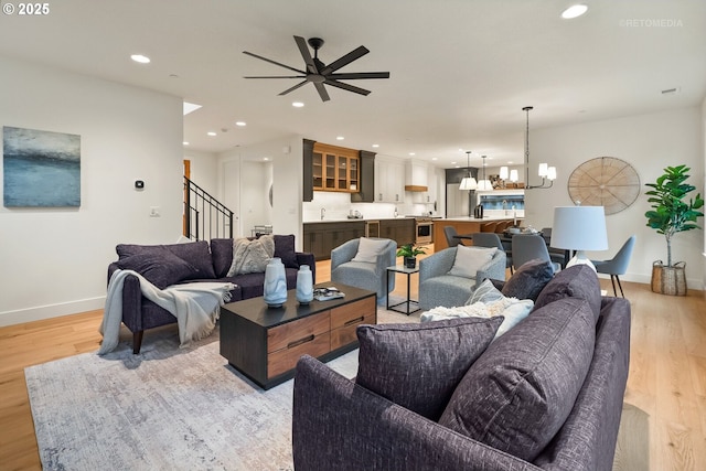 living room featuring light hardwood / wood-style flooring and ceiling fan with notable chandelier