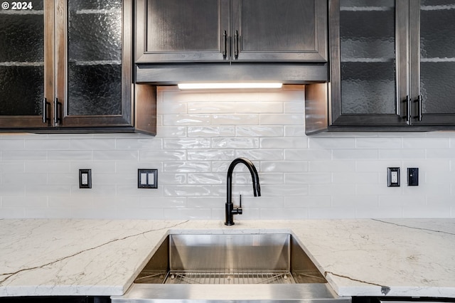 kitchen with light stone counters, sink, and decorative backsplash