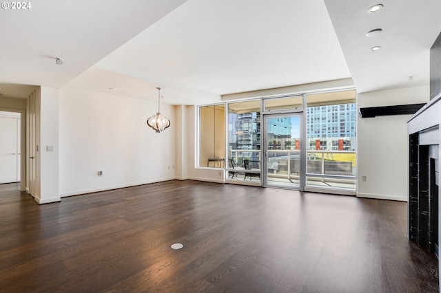 unfurnished living room with floor to ceiling windows, dark hardwood / wood-style floors, and a chandelier