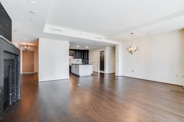 unfurnished living room featuring visible vents, baseboards, dark wood finished floors, a fireplace, and a notable chandelier