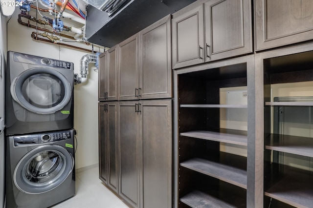 laundry room featuring cabinets and stacked washer / drying machine