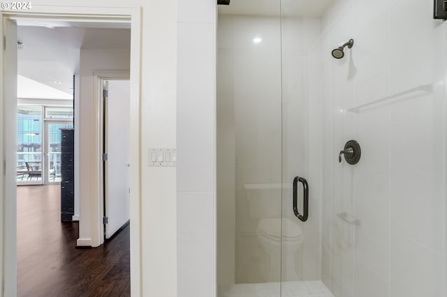 bathroom featuring walk in shower, toilet, and wood-type flooring