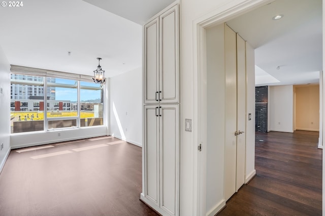 hall featuring a chandelier, baseboards, and dark wood-style flooring