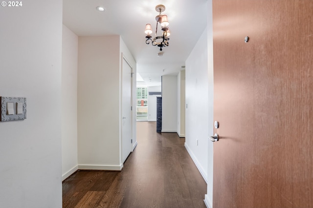 hall featuring an inviting chandelier, baseboards, and wood finished floors