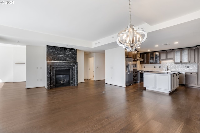 kitchen with a fireplace, stainless steel appliances, a kitchen island, an inviting chandelier, and dark hardwood / wood-style floors