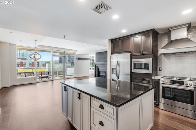 kitchen featuring a fireplace, appliances with stainless steel finishes, a center island, custom exhaust hood, and dark stone counters