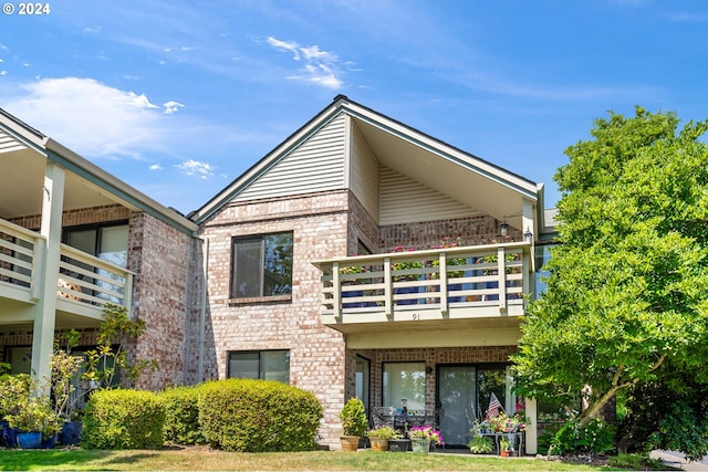 back of property featuring brick siding and a balcony