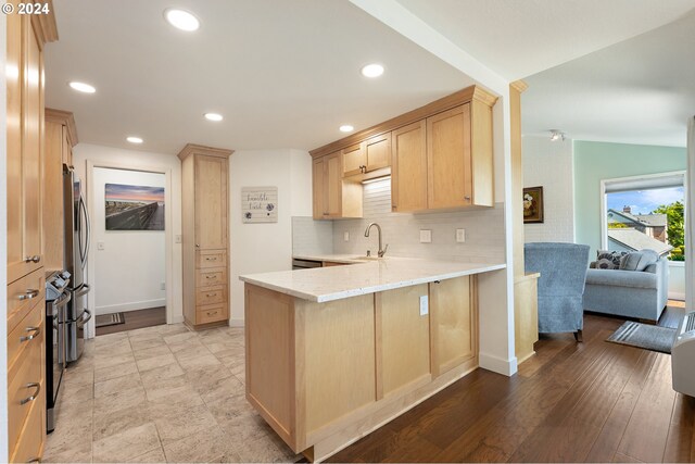 kitchen featuring backsplash, a sink, a peninsula, light brown cabinets, and recessed lighting