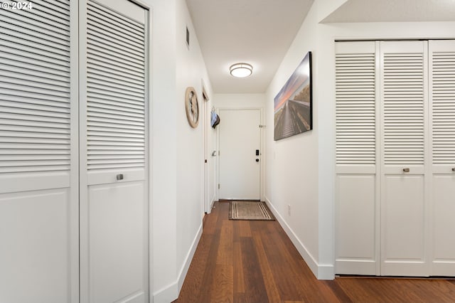 hallway with baseboards, dark wood-style floors, and visible vents