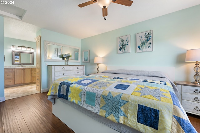 bedroom with a ceiling fan, a sink, wood finished floors, and ensuite bath