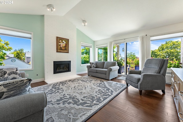 living area with a healthy amount of sunlight, a fireplace, dark wood-style flooring, and lofted ceiling