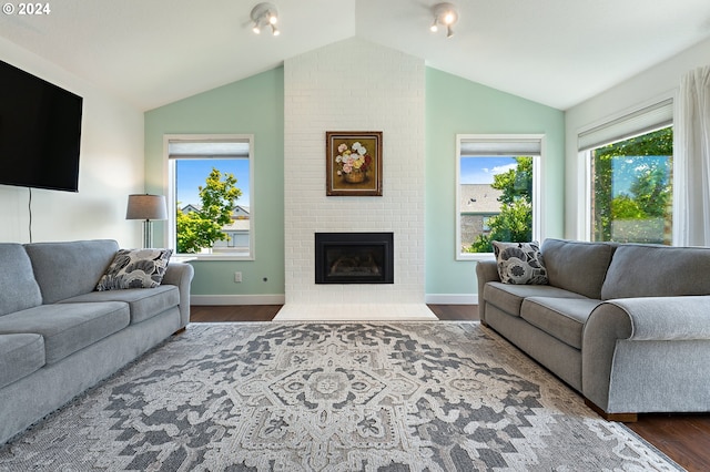 living area featuring a healthy amount of sunlight, a fireplace, wood finished floors, and lofted ceiling