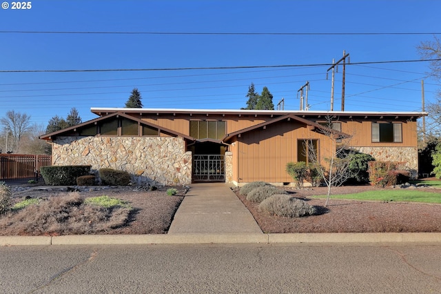 view of front of home featuring stone siding and fence