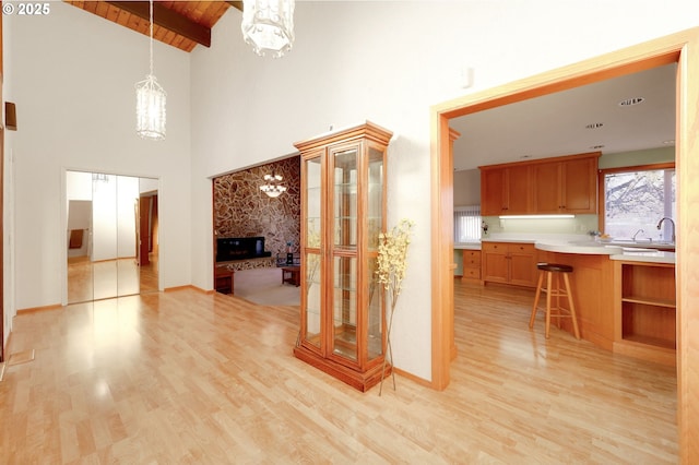 interior space with wooden ceiling, a high end fireplace, baseboards, light wood-style floors, and an inviting chandelier