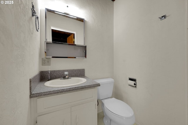 half bathroom with toilet, a textured wall, and vanity