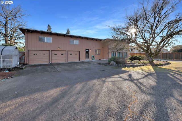 view of front facade featuring a garage, fence, and aphalt driveway