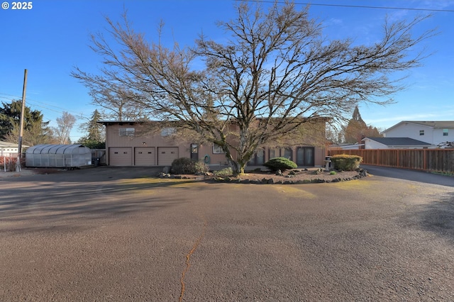 view of front of home with aphalt driveway and fence