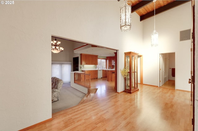 unfurnished living room featuring a notable chandelier, visible vents, light wood-style floors, wood ceiling, and beamed ceiling