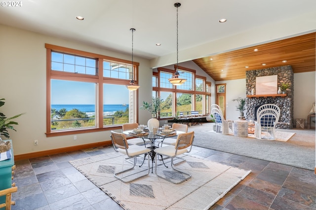 dining space with lofted ceiling, a water view, a healthy amount of sunlight, and a stone fireplace