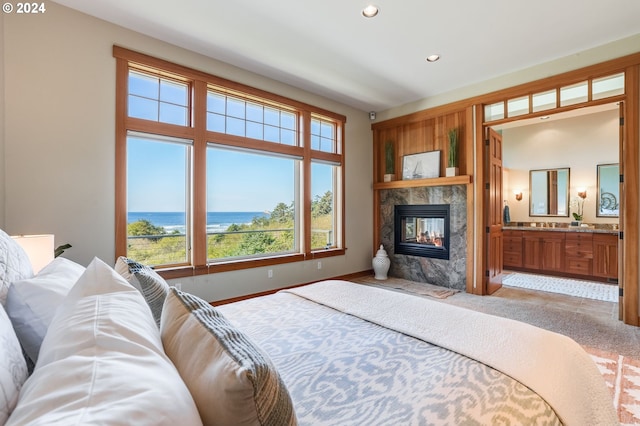 bedroom featuring light carpet, a multi sided fireplace, a water view, and ensuite bathroom