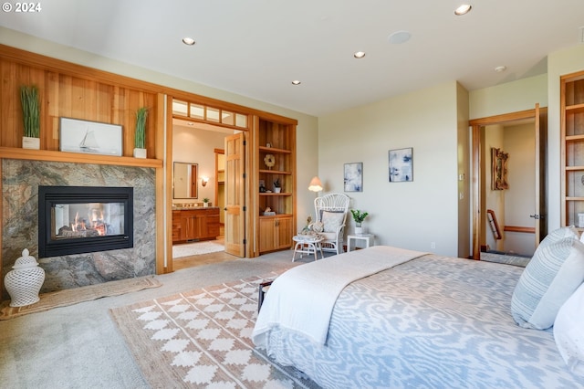 bedroom featuring connected bathroom, a fireplace, and light colored carpet