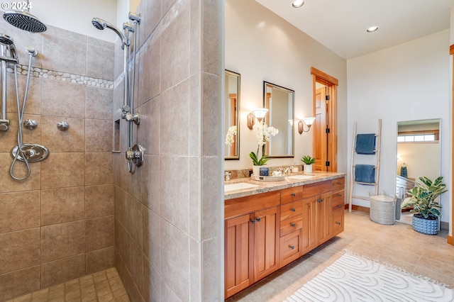 bathroom featuring tiled shower, vanity, and tile patterned flooring