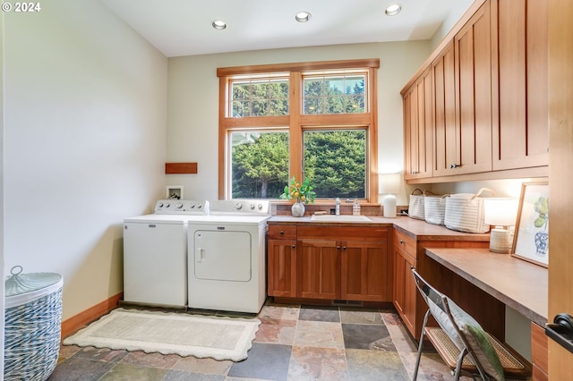 washroom with cabinets, washer and dryer, and sink