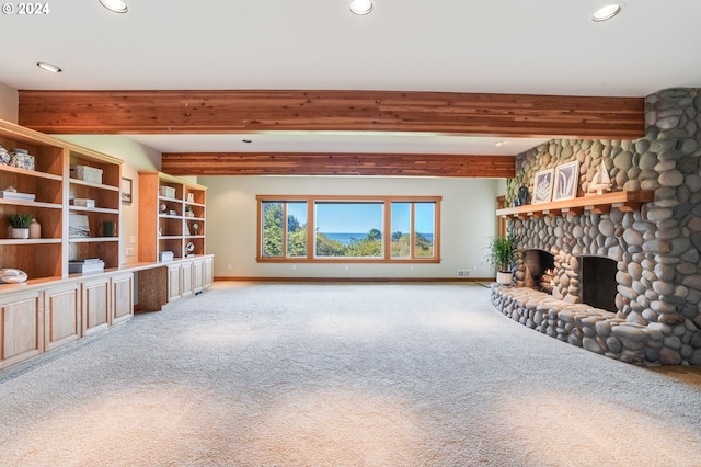 unfurnished living room with a stone fireplace, beam ceiling, and light colored carpet